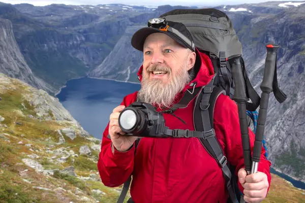 Sırt çantalı sakallı turist fotoğrafçı dağlardaki doğanın güzelliğini fotoğraflıyor. Dağlarda doğa yürüyüşleri