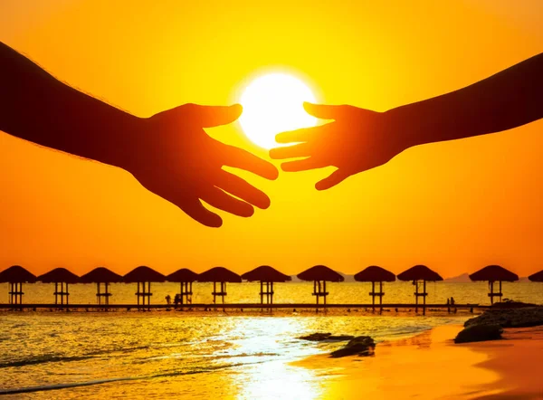 silhouette of male and female hands against the backdrop of the setting sun at an ocean resort. the concept of communication and the desire for intimacy in society and family