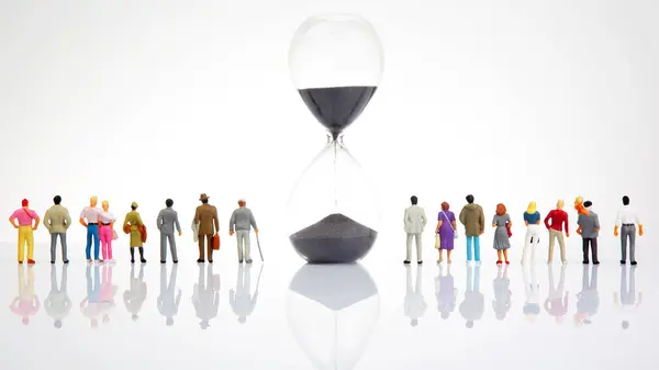 miniature people. group of different people stand near an hourglass against a white background. concept of people life time in society.