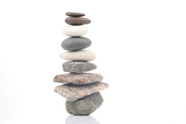 Beyaz zemin üzerinde istiflenmiş taşlar piramidi. Hayatta dengeleme ve denge
