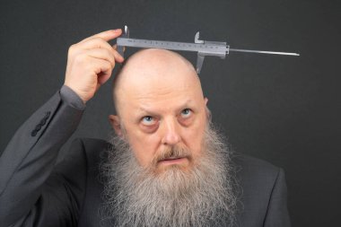 Kel sakallı adam kafasının genişliğini kalibre ile ölçer.