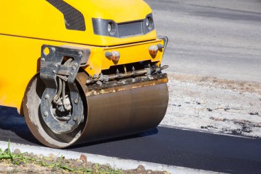 Asfalt silindiri yayalar için bir yol onarıyor