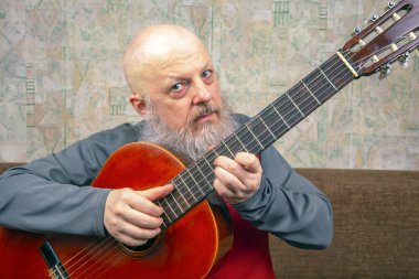 Sakallı kel adam klasik gitar çalar