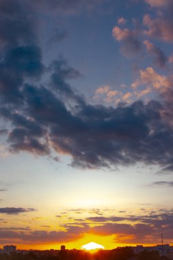 Günbatımından sonraki akşam gökyüzü büyüleyici bir mavi ve ateşli portakallar karışımı sergiliyor, narin bulutlar huzur sahnesine doku ve derinlik katıyor.