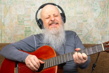 Sakallı kel adam klasik gitar çalar