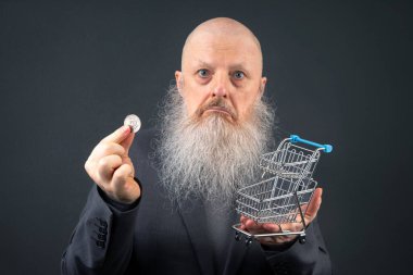 Elder in a Suit Holding a Coin and a Tiny Shopping Cart. Ekonomi ve Perakendenin Kavramsal Temsili