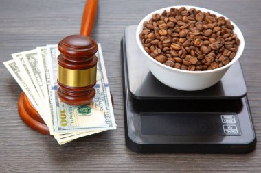 Tahta bir tokmak ve ahşap bir yüzey üzerinde Amerikan parasıyla çevrili bir kâse içindeki kahve çekirdekleri çarpıcı bir fotoğraf adalet ve ticaret temalarını çağrıştırıyor..