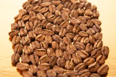 Işıl ışıl altın bir yüzey üzerinde kavrulmuş kahve çekirdekleri oval düzenleme, onların dünyevi renkleri ve doğal ışıltıları vurgulanıyor. Kahve dükkanı promosyonları için harika..