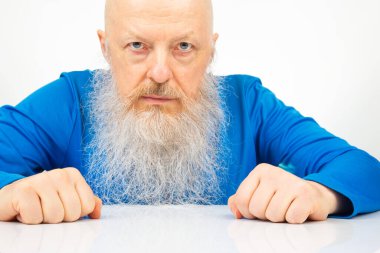 Açık arkaplanda büyük gri sakallı ciddi bir adamın portresi..