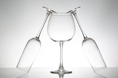 Üç kristal berraklığında çeşitli şekillerde şarap kadehi yan yana duruyor. Yansımaları parlak bir yüzey üzerinde parıldıyor. Lüks bir yaşam tarzı görüntüsü için ideal..