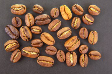 Kavrulmuş kahve çekirdekleri, toprak renkler ve koyu bir yüzeye yayılmış görünür dokular. Kahve dükkanı pazarlama ve mutfak tasarımları için harika.