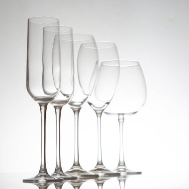 Uzun saplı beş boş şarap kadehinden oluşan sofistike bir düzenleme. Cilalı bir masaya yansıyor. Güzel bir yemek için mükemmel..