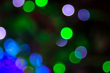 Karanlık bir yüzeyde bulanık altın ve renkli bokeh ışıkları, sıcak, odak dışı bir estetik ile neşeli veya kaprisli bir havayı çağrıştırıyor