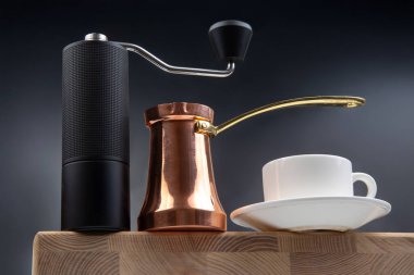 Siyah kahve öğütücüsü, bakır peynir ve beyaz bardak, koyu mavi arka planda, kahve kültürü için ideal..