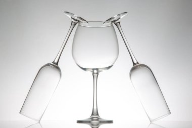 Üç kristal berraklığında çeşitli şekillerde şarap kadehi yan yana duruyor. Yansımaları parlak bir yüzey üzerinde parıldıyor. Lüks bir yaşam tarzı görüntüsü için ideal..