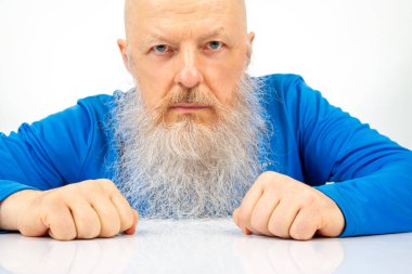 Açık arkaplanda büyük gri sakallı ciddi bir adamın portresi..