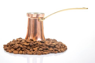 Beyaz arka planda kahve çekirdekleri ile çevrili bakır saplı klasik Türk kahve makinası, kültürel içecekler ve yemek içecekleri için uygun.