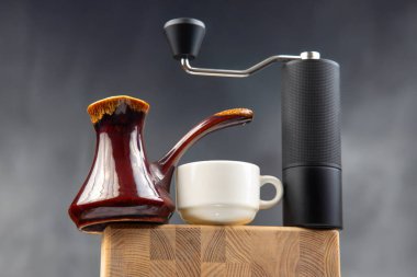 Siyah bir el değirmeni, bakır bir kahve makinesi ve çay tabağı olan beyaz fincan, koyu mavi arka planda, kahve demleme seansları için mükemmel..