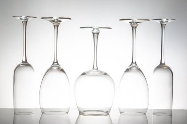 Beş kristal berraklığında çeşitli şekillerde şarap kadehi yan yana duruyor. Yansımaları parlak bir yüzey üzerinde parıldıyor. Lüks bir yaşam tarzı görüntüsü için ideal..