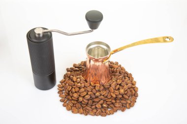 Modern manuel kahve öğütücüsü, bakır bir Türk çerezi ve otantik Türk kahvesi demlemek için gerekli malzemelerin sergilendiği beyaz bir zemin üzerinde kahve çekirdekleri..