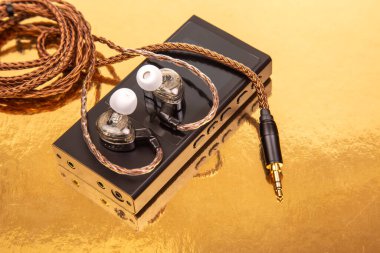 Parlak, siyah bir ses oynatıcının üzerinde dokuma kablosu olan kablolar, yansıtıcı altın bir yüzeye kurulmuş. Teknoloji, ses ve modern tasarım kavramları için ideal.