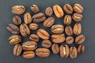 Kavrulmuş kahve çekirdekleri, toprak renkler ve koyu bir yüzeye yayılmış görünür dokular. Kahve dükkanı pazarlama ve mutfak tasarımları için harika.