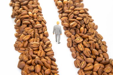 Kahve çekirdekleri arasında yol alan takım elbiseli minicik bir figürün kavramsal görüntüsü kahve ticareti kariyerini simgeliyor.