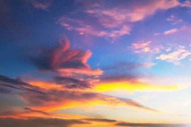 Ufukta parlak bir gün batımı turuncu, pembe ve mavi renklerden oluşan renkli bir gökyüzü. Dağınık bulutlar güneş ışığını yansıtıyor, sakin ve resimsel bir sahne yaratıyor, doğa için mükemmel.