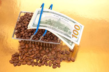 Kahve çekirdekleri ile dolu sepet, bir tabaka banknotun üzerinde duruyor. 100 dolarlık banknot, kahve tarımı ve finans sektörünün kesişmesini sembolize ediyor..