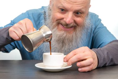  Kahkahalar ahşap masa sahnesini aydınlatır. Kahvesini fincana dökerken.