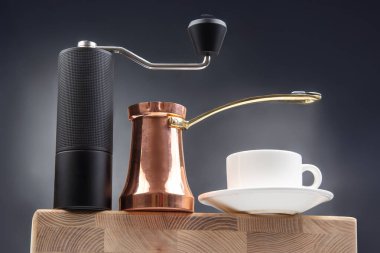 Siyah kahve öğütücüsü, bakır peynir ve beyaz bardak, koyu mavi arka planda, kahve kültürü için ideal..