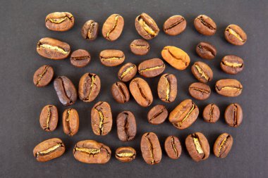 Yüksek çözünürlüklü kahve çekirdekleri, zengin tonlarda ve koyu dokulu arka planda bölünmüş yüzeyler. Kahve kültürü ve içecek imgeleri için ideal..