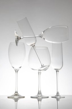 İnce saplı beş şarap kadehinden oluşan şık bir sıra, yansımaları parlak bir masa üzerinde çarpıcı bir etki yaratıyor, modern yemek ve şarap estetiği için ideal..