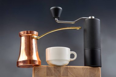 Siyah kahve öğütücüsü, bakır peynir ve beyaz bardak, koyu mavi arka planda, kahve kültürü için ideal..