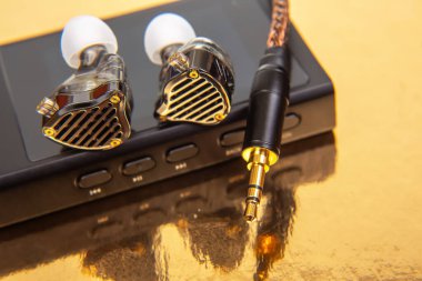 Siyah bir müzik çaların üzerine örülmüş kabloyla altın yansıtıcı bir yüzeye karşı zarif kablo kulaklıklar. Teknoloji, ses ve modern tasarım stok görüntülemesi için uygundur.