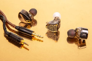 Üç kulaklık, örgülü kablolar ve 3.5 mm 'lik altın bir yüzeye takılı, ses aksesuarları ve teknolojik ekipmanlar için harika..