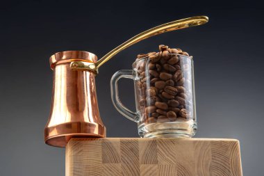 Altın saplı klasik bir çakmak ve içi kahve çekirdekleriyle dolu bir bardak tahta kesme tahtasının üzerinde duruyor. Kahve kültürünü ve geleneği kutlayan rafine bir natürmort..