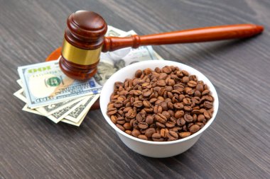 Mahkeme tokmağı, içinde kahve çekirdekleri olan bir kâse, ahşap bir yüzey üzerinde hukukun, paranın ve ticaretin kesişimini tasvir eden Amerikan para birimine dayanır..