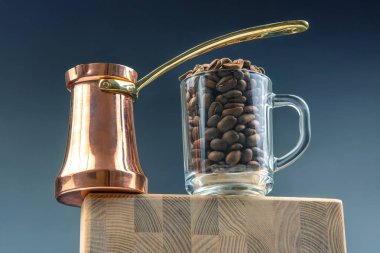 Altın saplı klasik bir çakmak ve içi kahve çekirdekleriyle dolu bir bardak tahta kesme tahtasının üzerinde duruyor. Kahve kültürünü ve geleneği kutlayan rafine bir natürmort..