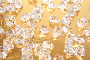 Parlak altın bir zemin üzerinde şeffaf mücevher benzeri kristaller koleksiyonu göz alıcı ve zengin bir estetik yaratıyor. Mücevher ya da tatil dekorasyonu için ideal..