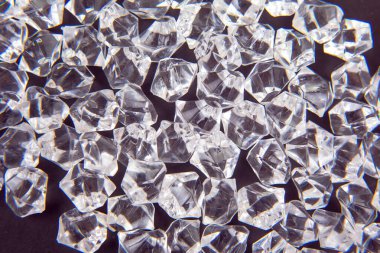 Parlak kristaller karanlık bir yüzeye dağılmış, ışığı güzel yansıtıyor, lüks ve zarafet temalı tasarımlar veya şenlikli dekorasyonlar için mükemmel..