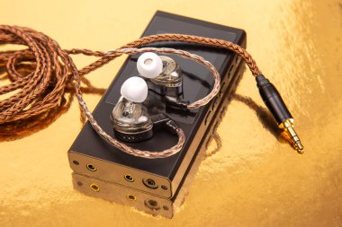 Parlak, siyah bir ses oynatıcının üzerinde dokuma kablosu olan kablolar, yansıtıcı altın bir yüzeye kurulmuş. Teknoloji, ses ve modern tasarım kavramları için ideal.