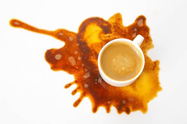 Beyaz kahve fincanı ve espresso, kaotik kahverengi bir dökülmenin ortasında duruyor. Sanat ve kazayı minimalist beyaz bir yüzeyde harmanlıyor.