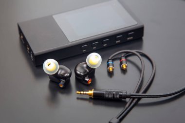 Çıkarılabilir kablolu yüksek kaliteli kulak monitörleri, siyah kulaklıklar, kulak uçları ve 3.5 mm 'lik altın kaplamalı kriko. Odiyofiller ve müzisyenler için ideal. Parlak gri bir arkaplanda izole edilmiş.