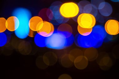 Koyu bir zemin üzerinde altın ve renkli ışık çemberleri oluşturan canlı bir bokeh etkisi yumuşak, bulanık renkleri olan neşeli ve rüya gibi bir atmosfer yaratıyor..