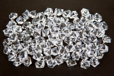 Karanlık bir yüzeyde şeffaf kristaller parıldıyor, göz kamaştırıcı bir efektle ışığı yansıtıyor, şenlikli, lüks veya takıdan esinlenilmiş bir sahne yaratmak için ideal..