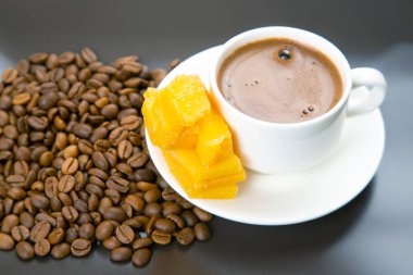 Beyaz bir fincanda üst üste espresso, siyah bir masada peynir çubukları ve kahve çekirdekleri ile eşleştirilmiş, kırsal yemek sahnesi için mükemmel.