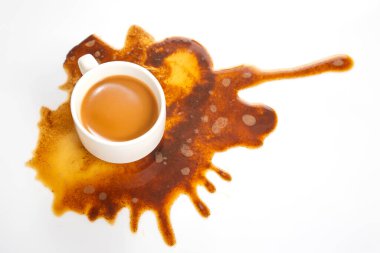 Beyaz bir fincandan dökülen zengin kahve, bozulmamış bir yüzeye çarpıcı bir kahverengi desenle yayılıyor, yemek ve yaşam tarzı temaları için ideal.