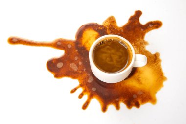 Beyaz bir fincandan dökülen zengin kahve, bozulmamış bir yüzeye çarpıcı bir kahverengi desenle yayılıyor, yemek ve yaşam tarzı temaları için ideal.