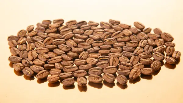 Işıl ışıl altın bir yüzey üzerinde kavrulmuş kahve çekirdekleri oval düzenleme, onların dünyevi renkleri ve doğal ışıltıları vurgulanıyor. Kahve dükkanı promosyonları için harika..